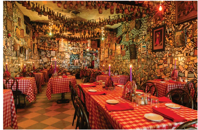 Cozy vintage restaurant interior with red checkered tablecloths, mosaic walls, hanging bottles, and candlelit tables
