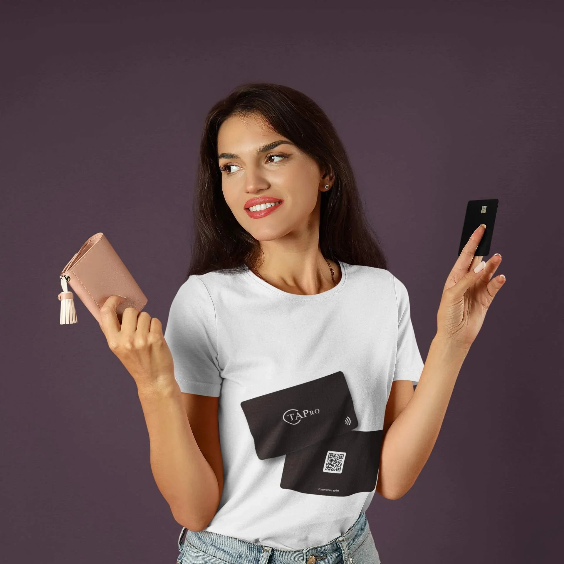 Young woman holding a light pink wallet and a black digital NFC card against dark background