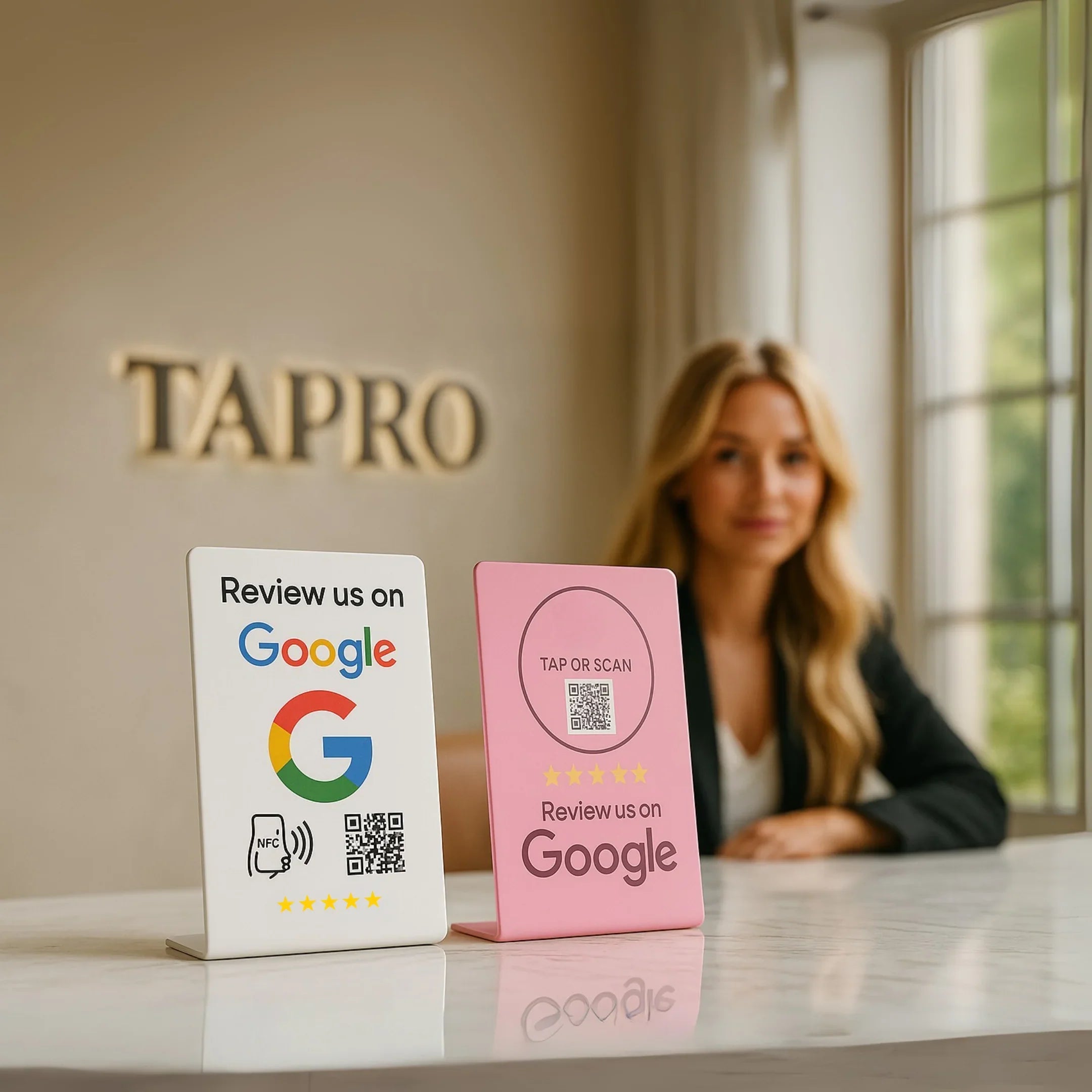 Two Google review stands with QR codes on a table, woman blurred in background, TAPRO logo on wall