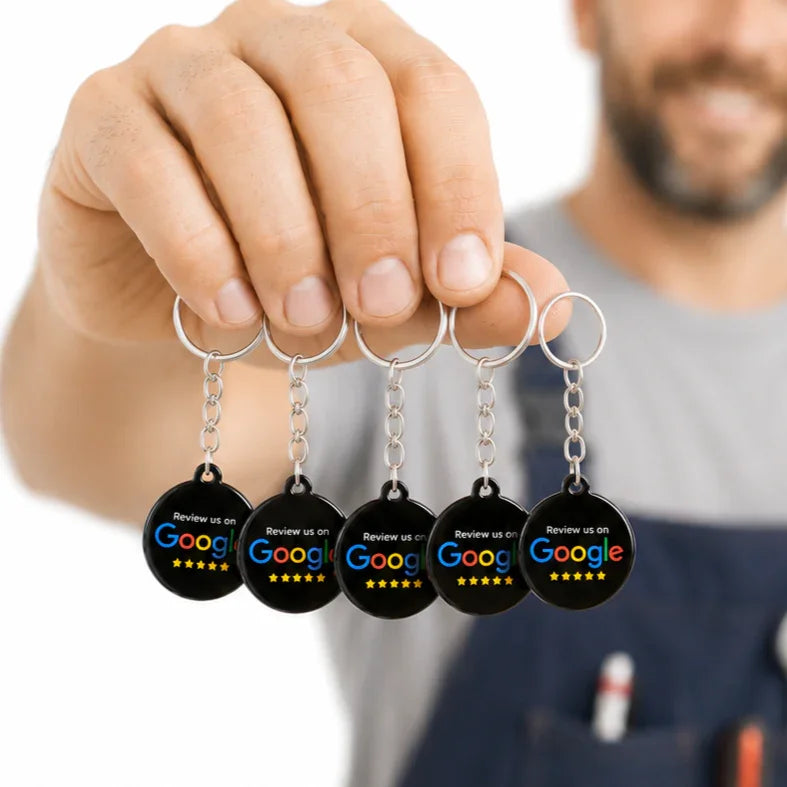 Hand holding 5 black circular Google review keychains with NFC QR for customer feedback and local business reputation growth